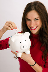 Image showing Save a Quarter Smiling Woman Drops Quarter into Piggy Bank