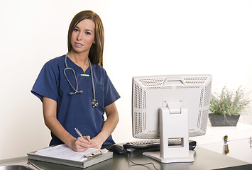 Image showing Working Nurse Fills Out Chart at Workstation