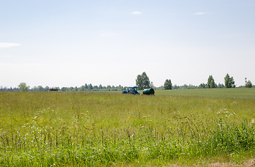 Image showing working tractor with water tank in pasture meadow 