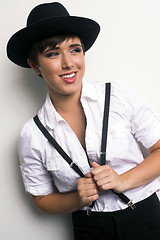 Image showing Young Androgynous Woman Stands Wearing Hat Suspenders White Back