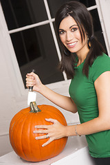 Image showing Happy Attractive Woman Cuts Top Off Pumpkin Halloween Jackolante