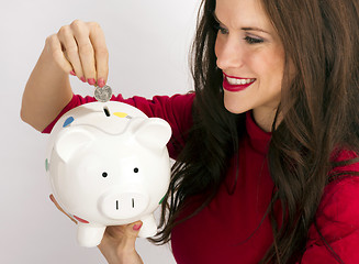 Image showing Pretty Happy Brunette Woman Drops Quarter Coin Savings Bank