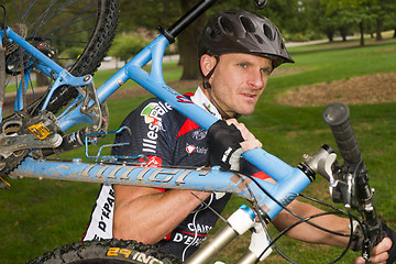 Image showing Serious Male Bicycle Racer Carrying Bike During Iron Man Triathl