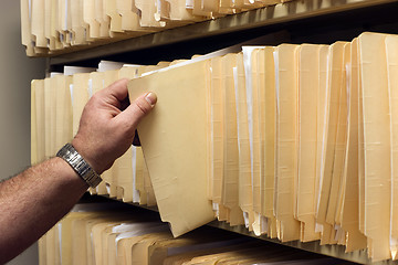 Image showing Human Hand Pulls File Folder off Shelf of Client Files