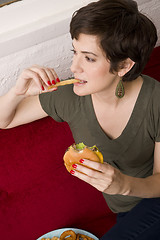 Image showing Woman Eating Burger Fries Lunch Sofa Living Room Meal Time