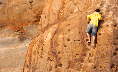 Image showing Young Boy Climbs Sandstone Rock Wall Beach Front Male Climber