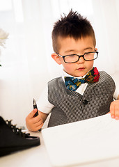 Image showing Young Boy Plays Intellectual Business Man Signing Papers at Desk