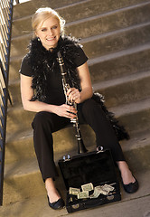 Image showing Female Street Performer Sits on Steps Clarinet Case With Tips