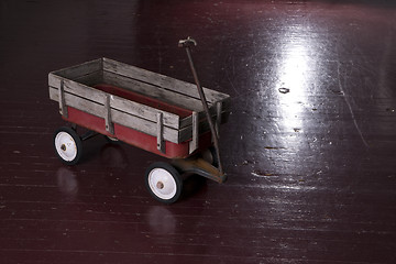 Image showing Vintage Rusted Red Metal Utility Wagon on Old Wood Floor