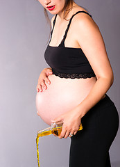 Image showing Pregnant Woman Expecting Baby Pours Alcohol Empties Whiskey Bott