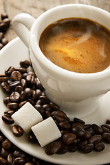 Image showing Small cup of black coffee on a brown background with coffee bean