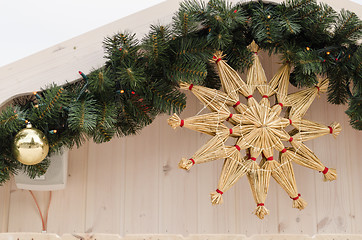 Image showing christmas star twisted from straw on house corner  