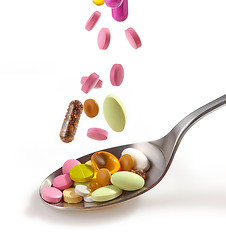 Image showing various pills falling into spoon