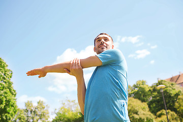 Image showing smiling man stretching outdoors