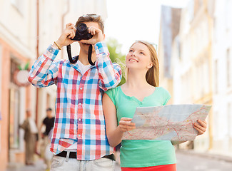 Image showing smiling couple with map and photo camera in city