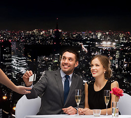 Image showing smiling couple paying for dinner with credit card