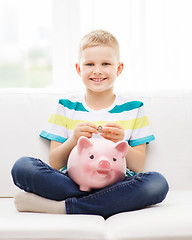 Image showing smiling little boy with piggy bank and money