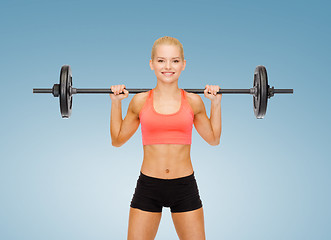 Image showing smiling sporty woman exercising with barbell