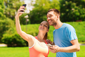 Image showing two smiling people with smartphones outdoors