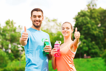 Image showing smiling couple with bottles of water outdoors