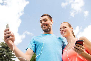 Image showing two smiling people with smartphones outdoors