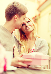 Image showing romantic happy couple with gift in the cafe