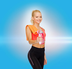 Image showing smiling sporty woman with water bottle and towel