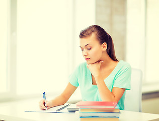 Image showing tired student writing in notebook