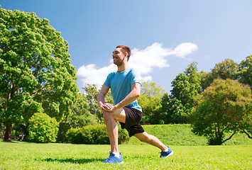 Image showing smiling man stretching outdoors