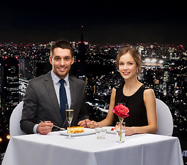 Image showing smiling couple eating dessert at restaurant