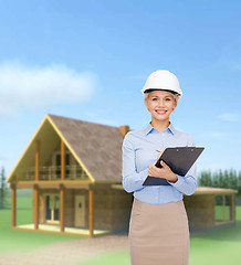 Image showing smiling businesswoman in helmet with clipboard