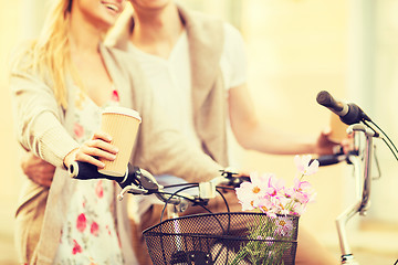 Image showing couple holding coffee and riding bicycle