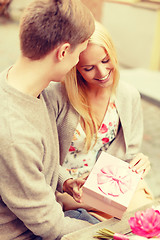 Image showing romantic happy couple with gift in the cafe