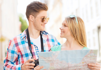 Image showing smiling couple with map and photo camera in city