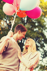 Image showing smiling couple with colorful balloons in park