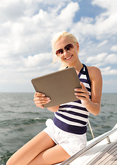 Image showing smiling woman sitting on yacht with tablet pc