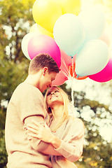 Image showing smiling couple with colorful balloons in park