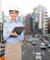 Image showing smiling businesswoman in helmet with clipboard