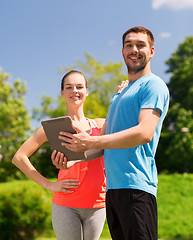 Image showing smiling couple with tablet pc outdoors