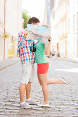 Image showing smiling couple with map and photo camera in city