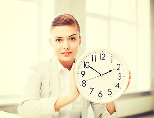 Image showing attractive businesswoman showing white clock
