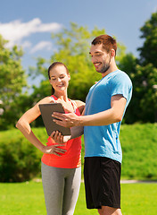 Image showing smiling couple with tablet pc outdoors