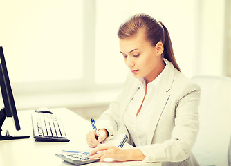Image showing businesswoman with notebook and calculator