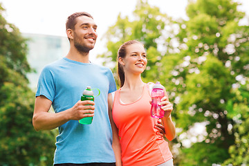 Image showing smiling couple with bottles of water outdoors