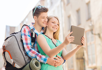 Image showing smiling couple with tablet pc and backpack in city