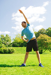 Image showing smiling man stretching outdoors