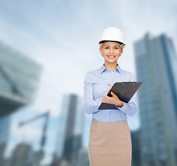 Image showing smiling businesswoman in helmet with clipboard