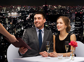 Image showing waiter giving menu to happy couple at restaurant