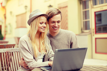 Image showing smiling couple with laptop computer in cafe