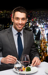 Image showing smiling man eating main course